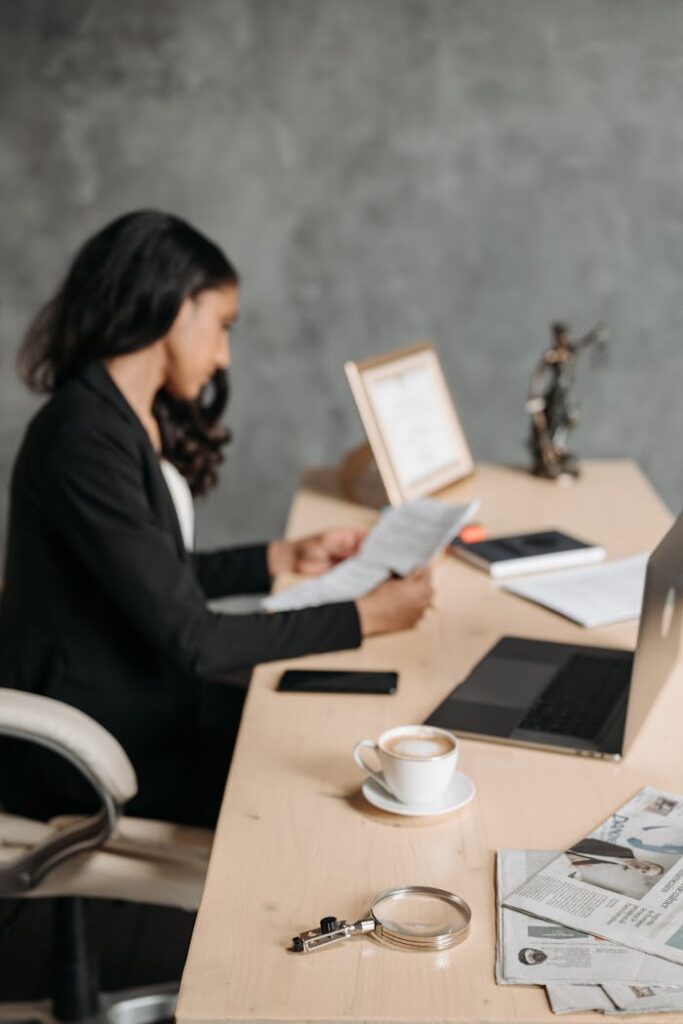 Nous choisir Asian woman in office attentively reading paperwork at a desk.