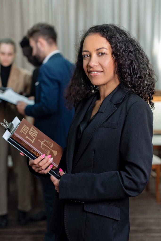 Nous choisir African American female lawyer holding a law book in an office setting, showcasing professionalism and legal expertise.